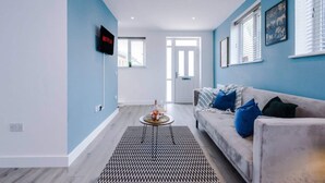 Un salon moderne avec un canapé, une table basse et un téléviseur fixé au mur.