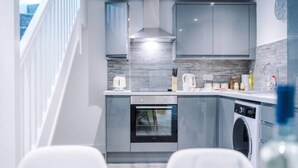 Une cuisine moderne avec des meubles gris, un four encastré, un lave-vaisselle et un évier en acier inoxydable.