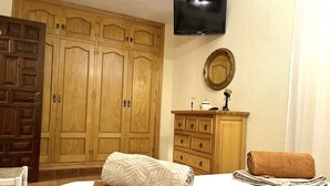 A bedroom with a bed, a wooden wardrobe, a television, a mirror, and a small cabinet. - EDMUNDO house with pool next to the beach (AN)
