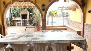 A patio with a brick barbecue, outdoor seating, and a pool. - EDMUNDO house with pool next to the beach (AN)