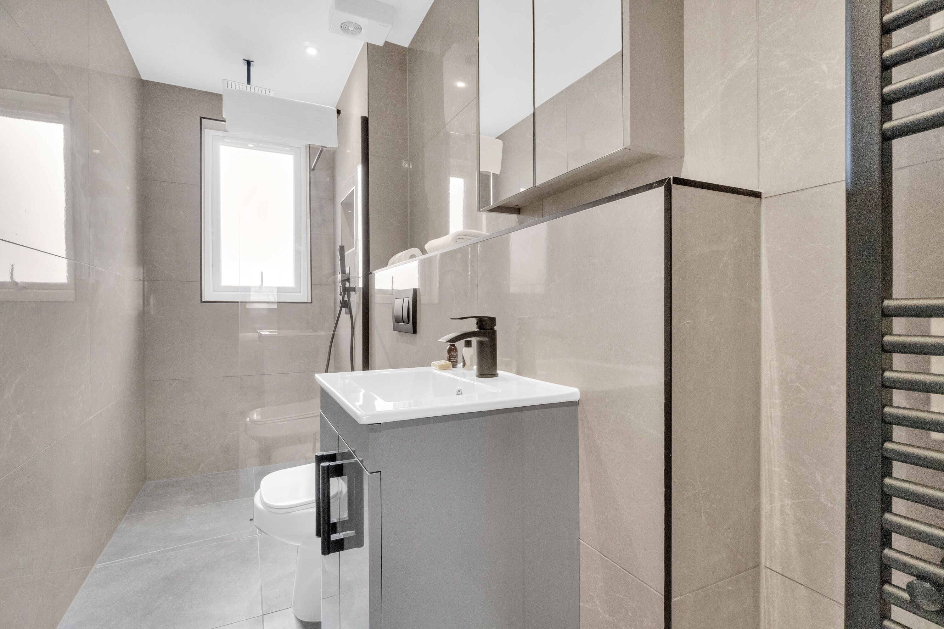 Un baño moderno con un lavamanos blanco, un inodoro y una zona de ducha.