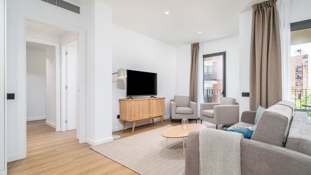 A modern living room with a sofa, armchairs, a coffee table, and a TV on a wooden cabinet.