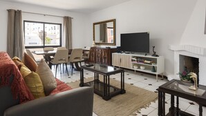 Un salon comprenant un canapé, une table basse, un téléviseur, une cheminée et un coin repas.