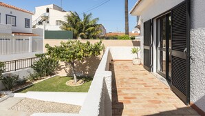 Un immeuble résidentiel avec un toit en tuiles, un petit jardin agrémenté de palmiers et un chemin en briques.