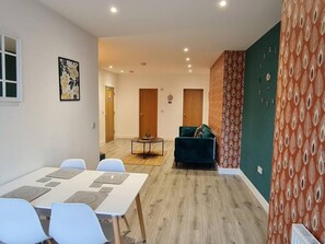 Ein modernes Wohnzimmer mit Essbereich, Holzboden und einer Wand in Grüntönen.