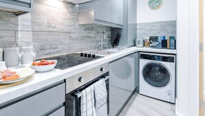 Een moderne keuken met een inbouwfornuis, een spoelbak en een wasmachine.
