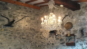 Ein rustikaler Raum mit Steinwand, Holzbalken, einer Kandelaber und einem rustikalen Hut an der Wand.