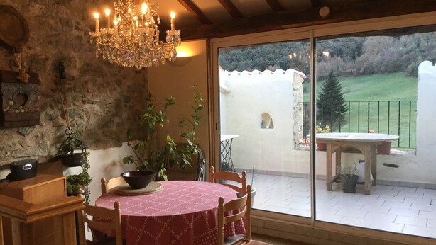 Ein Essbereich mit Tisch und Stühlen, einer Chandelier und Blick ins Freie.