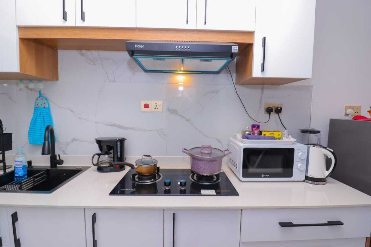 A compact kitchen with a gas stove, a microwave, and a kettle.
