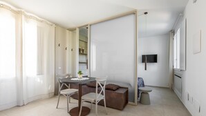 En moderne stue med spiseplads, sofa, TV og en skydedør til et køkken.