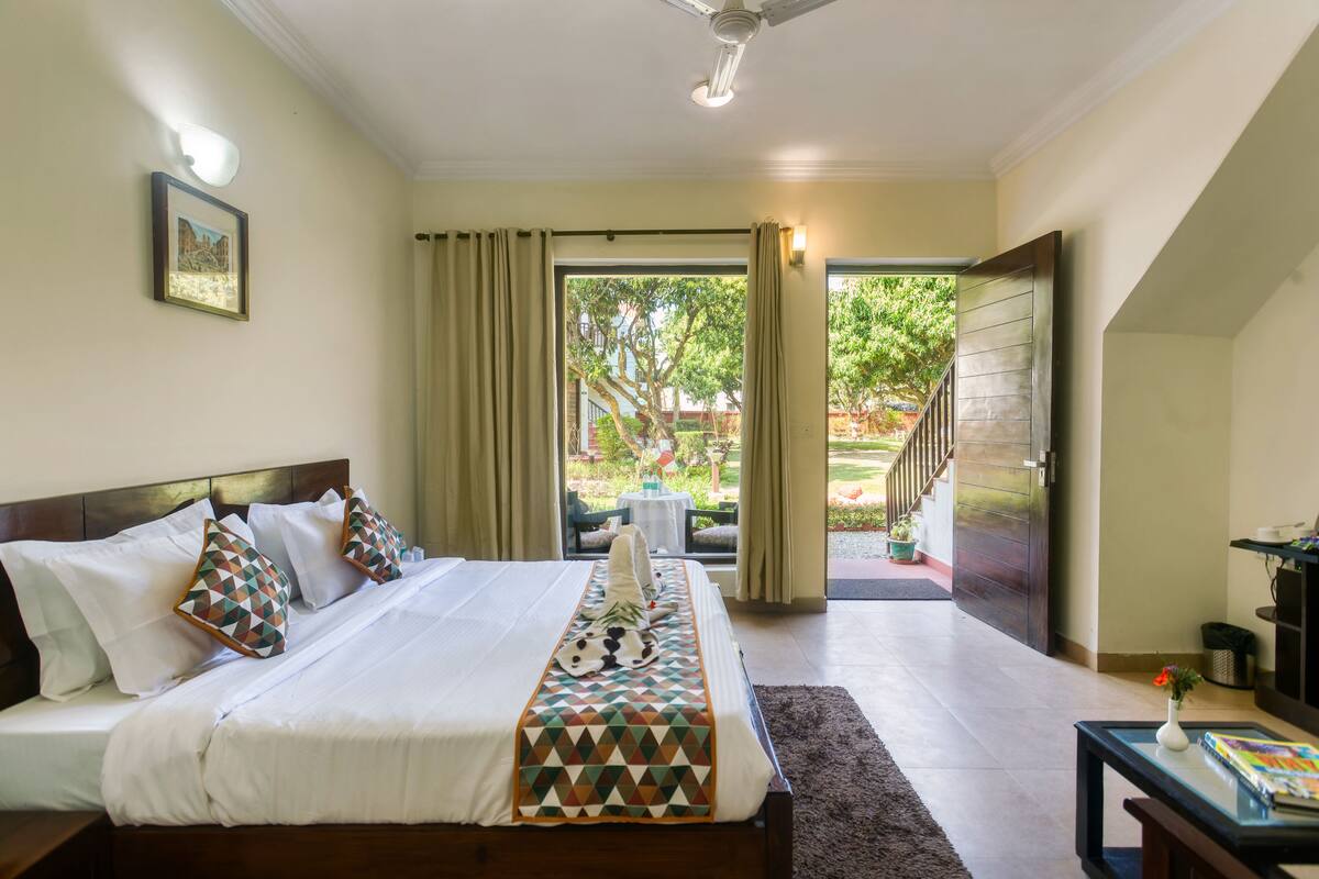 A hotel room with a bed, a nightstand, a window with curtains, and a view of the outside.