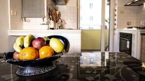 Una cocina con un frutero en la encimera, una ventana y una puerta que da a otra habitación.