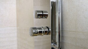 Un panel de control de ducha cromado con múltiples mandos y perillas, probablemente para regular la temperatura y el caudal del agua.