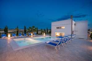 A modern pool area with lounge chairs and a building with large windows. - Villa Sikelia (Alcamo)