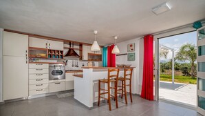 A modern kitchen with a central island, bar stools, and a sliding glass door leading to a balcony.