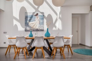 A modern dining room with a large painting, a blue vase, and a dining table set for six.