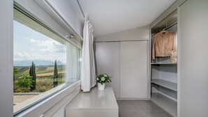 Ein modernes Badezimmer mit großem Fenster, einem weißen Waschtisch, einer Topfpflanze und einem aufgehängten Bademantel.