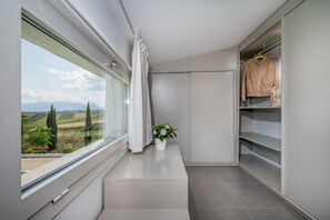Ein modernes Badezimmer mit großem Fenster, einem weißen Waschtisch, einer Topfpflanze und einem aufgehängten Bademantel.