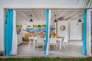 An open-plan living space with a dining area, kitchen, and a view of the outdoors. - Villa Sikelia (Alcamo)
