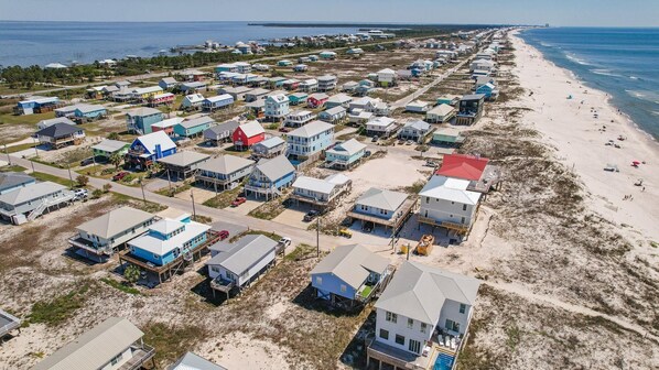 An aerial view of a coastal residential area with houses and a beach.