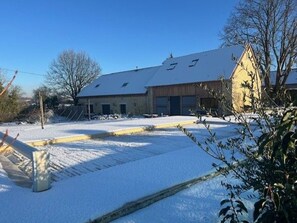 A building with a sloped roof, large windows, and a snow-covered ground.