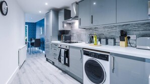 A modern kitchen with grey cabinets, a built-in microwave, a coffee station, and a washing machine. - One-bedroom by Media City UK by Belvilla (Manchester)