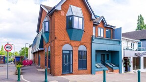 A two-story building with a brick facade, large windows, and a blue awning. - One-bedroom by Media City UK by Belvilla (Manchester)