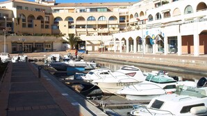 A marina with boats docked, a building with multiple balconies, and a clear sky. - Beautiful 2-room apartment in Sète with private parking (Sète)
