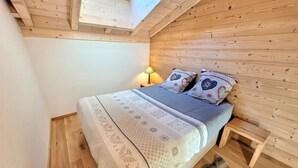Una habitación acogedora de madera con una cama, una mesita de noche y un tragaluz.