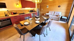 Una cocina moderna con armarios rojos, una mesa de comedor preparada para cuatro personas y un sofá en la sala.