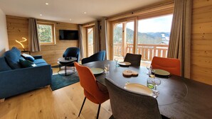 Ein gemütliches Zimmer mit Holzvertäfelung, einem Esstisch für zwei Personen und einer Couch mit an der Wand montiertem Fernseher.