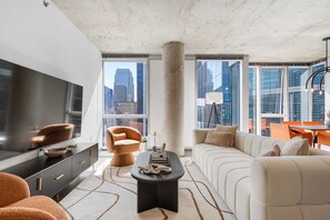 Una sala de estar moderna con un televisor grande, asientos cómodos y vistas a la ciudad.