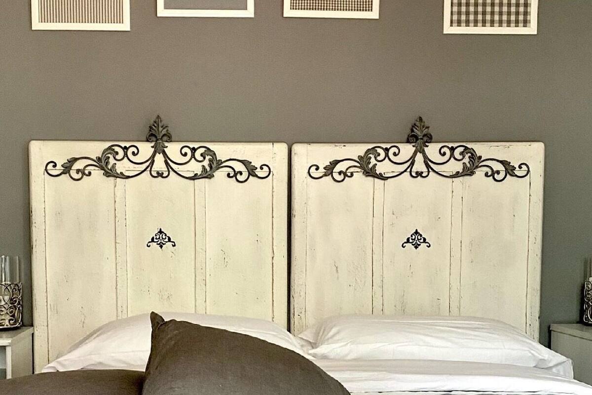 Un lit avec deux oreillers, une couvre-lit à rayures et une tête de lit agrémentée d’éléments décoratifs.
