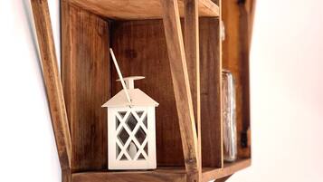 A wooden wall-mounted shelf with a white lantern and a jar.
