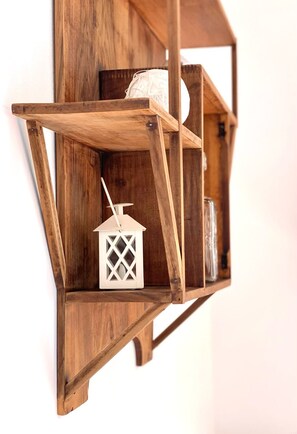 A wooden wall-mounted shelf with a white lantern and a jar.