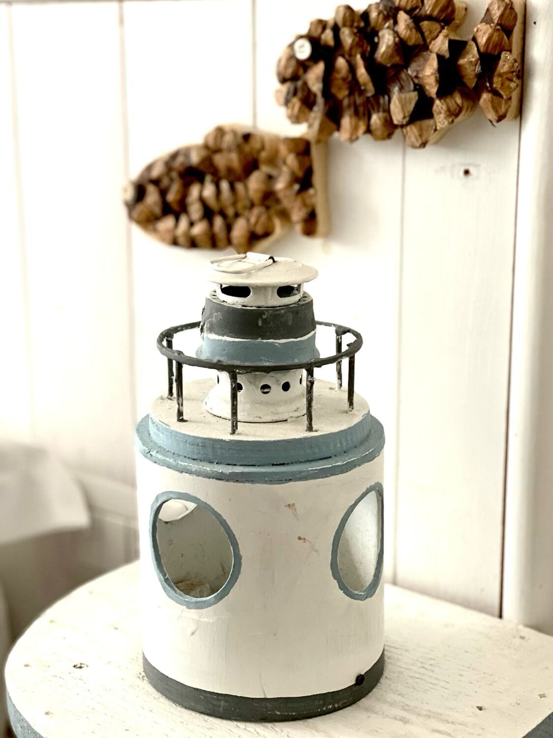 A white and blue lantern with circular windows on a white wooden table.