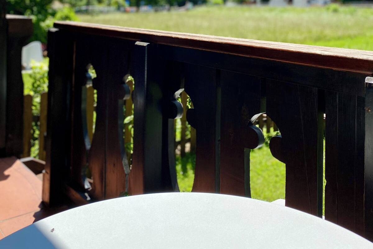 Une terrasse en bois offrant une vue sur un champ verdoyant et, au loin, sur une montagne.