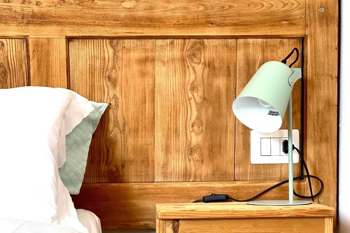 Une tête de lit en bois, avec une table de chevet et une lampe.