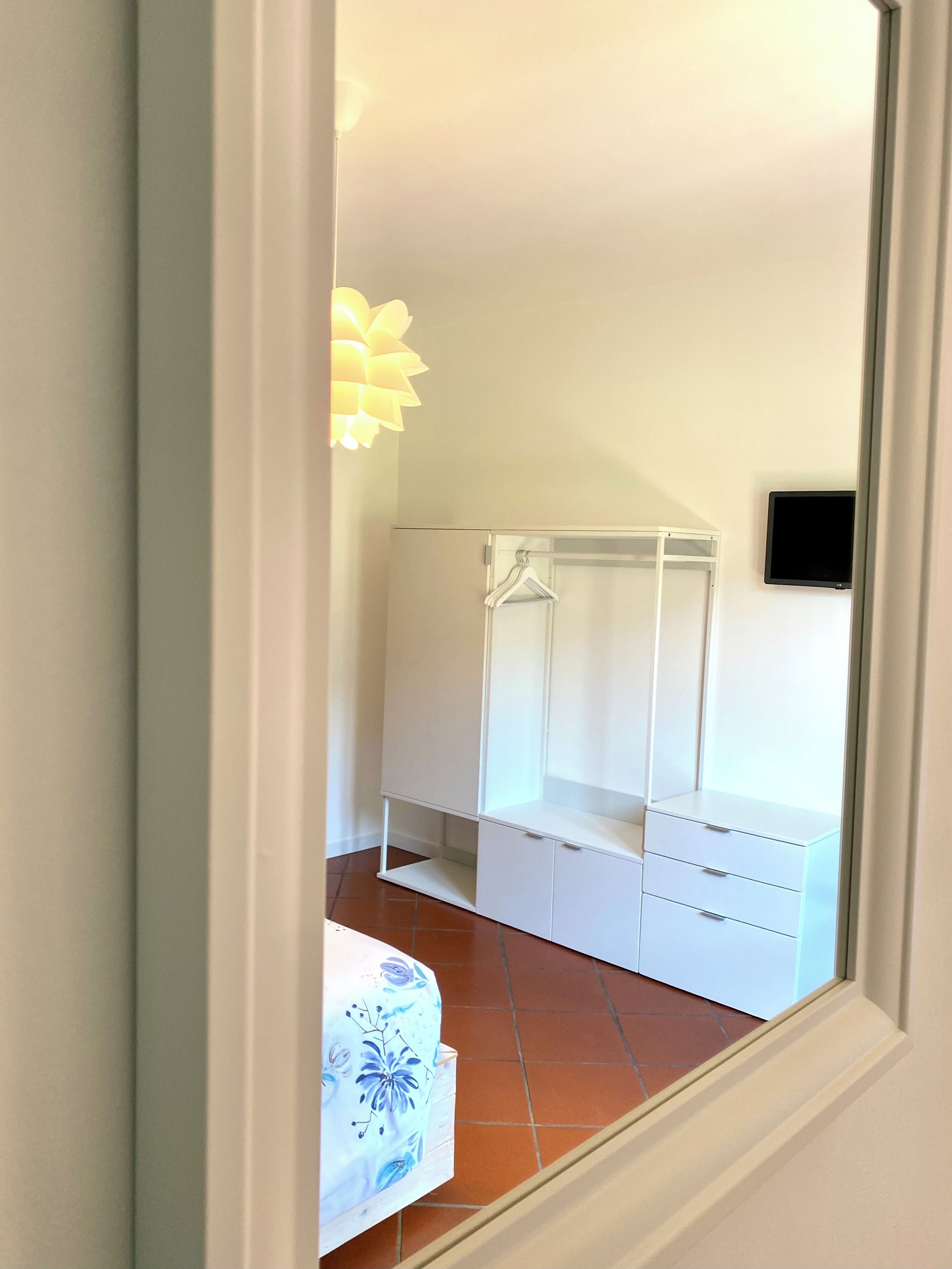 A bedroom with a bed, a wardrobe, and a television on the wall.