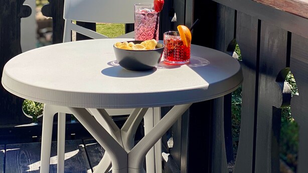 Un balcon avec une table, un saladier et deux boissons.