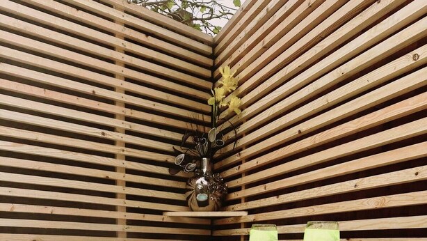 Un bain à remous avec un mur en lattes de bois et un vase décoratif.