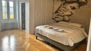 Ein Schlafzimmer mit einem großen Bett, Holzboden, einem Fenster und einer Wand mit einer strukturierten Wandmalerei.