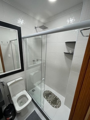 A modern bathroom with a glass-enclosed shower, a toilet, and a sink.