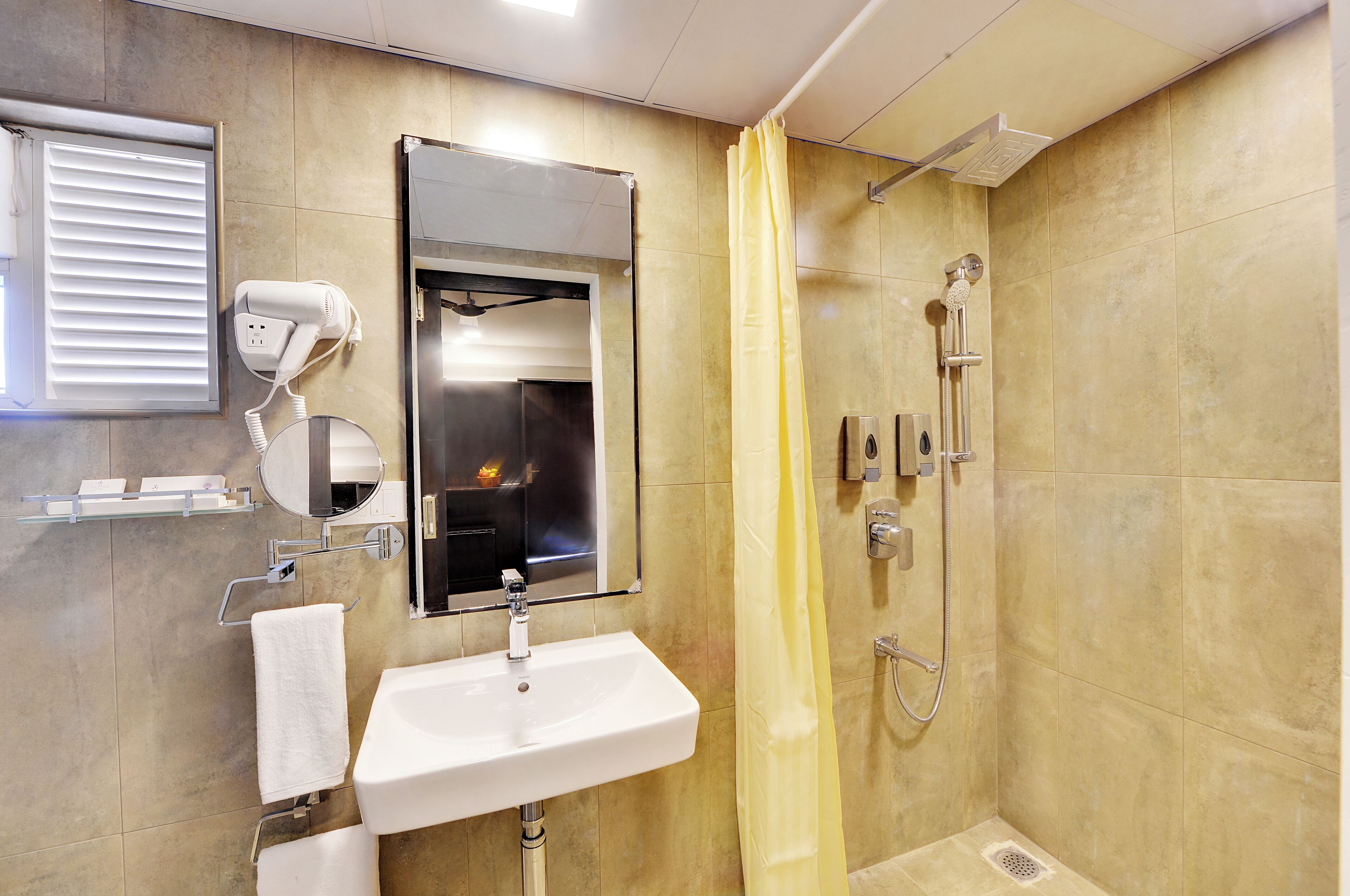 Un baño con lavamanos, espejo, secador de pelo, ducha y cortina de ducha amarilla.