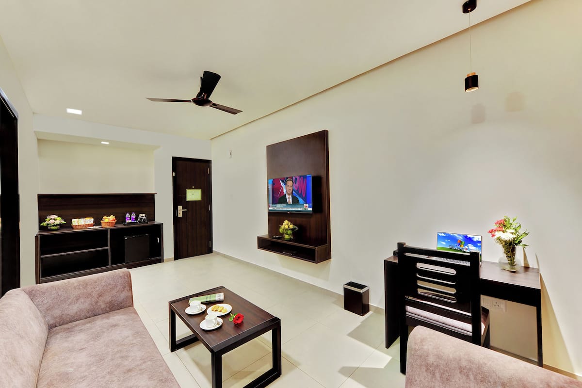 A modern living room with a sofa, coffee table, TV, and a ceiling fan.