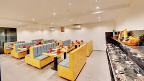 A restaurant with wooden booths and tables, a buffet counter with various food items, and air conditioning units on the walls. - The Lavender Hotel (Bengaluru)