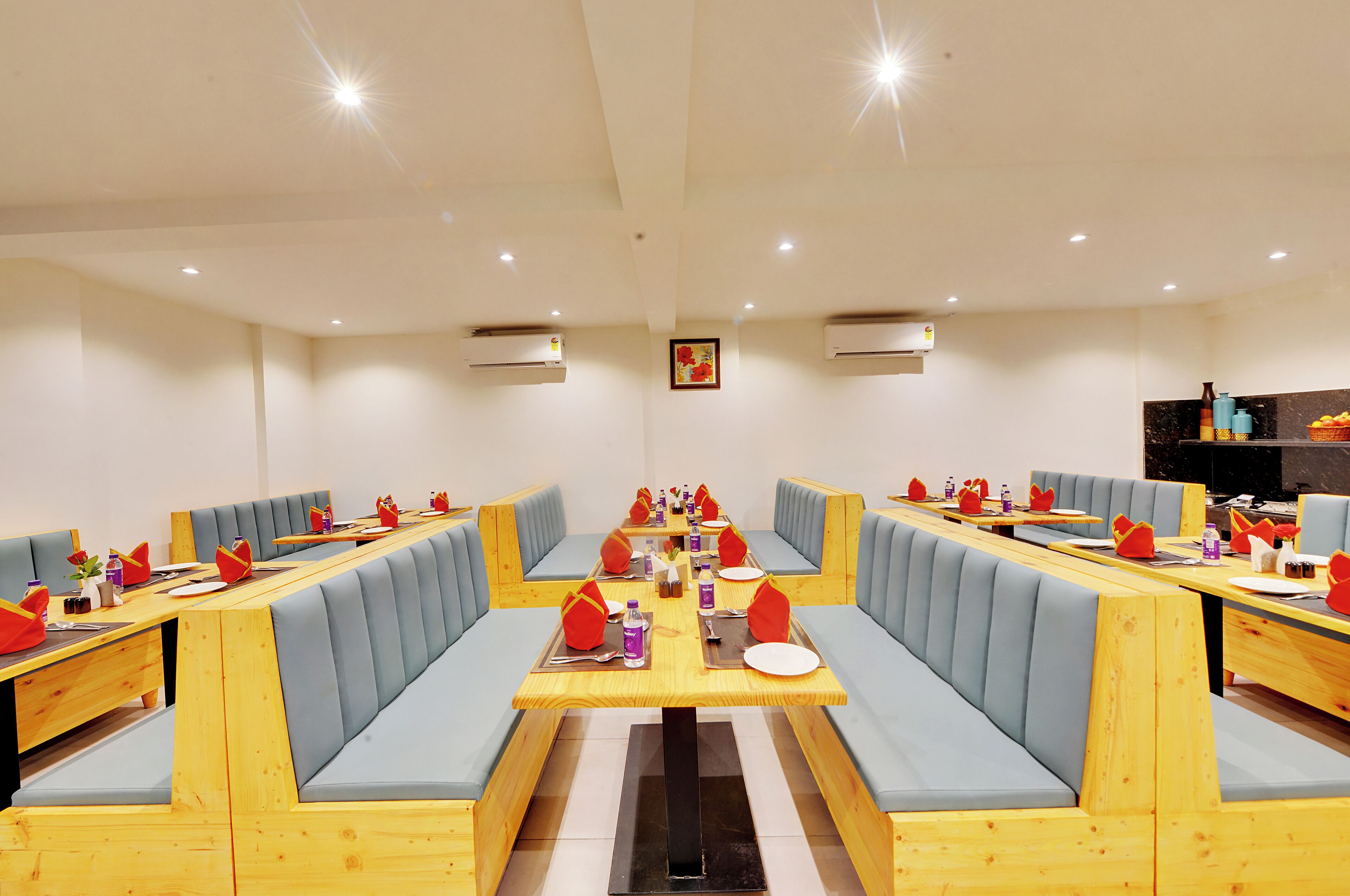 A restaurant with long communal tables and booths, equipped with tableware and condiments.