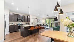 A modern kitchen with dark cabinets, a central island with bar stools, and pendant lighting.
