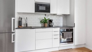 Eine moderne Küche mit weißen Schränken, einem Edelstahlkühlschrank, einer Mikrowelle und einem Backofen.