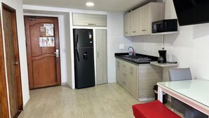 Una cocina compacta con refrigerador, microondas y estufa.
